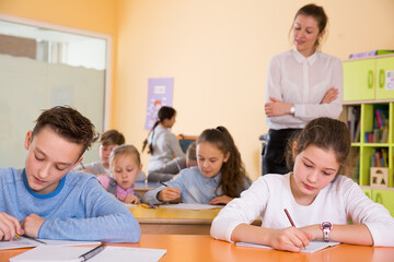 Obraz premium Young teacher woman and diligent schoolkids during lesson in classroom