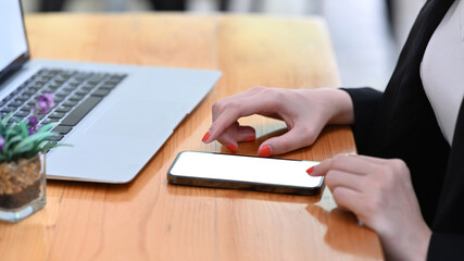 Close up view businesswoman sitting at office desk and using mobile phone.