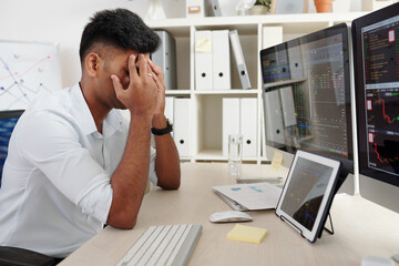 Fototapeta premium Stock market broker covering eyes with hands when sitting at table stressed after loosing a lot of money