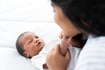 Newborn baby and young mother. Smiling mom with African American newborn on bed. family, love, happy and new life concept
