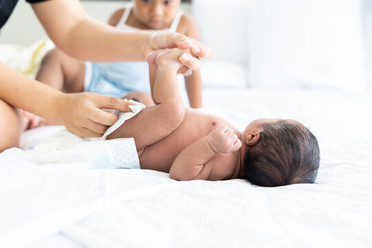 Mom Wiping Her Newborn Baby Skin, Face With Wet Wipes Carefully On Bed At Home. Family, Cleaning Wipe And Infant Concept