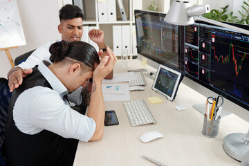 Fototapeta na wymiar Trader trying to reassure his colleague who lost a lot of money of hedge fund while investing