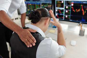 Trader patting sad desperate collegue on back reassuring him after he made bad investment