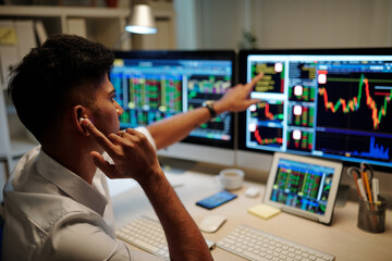 Emotional trader pointing at stock chart data when calling his colleague or client