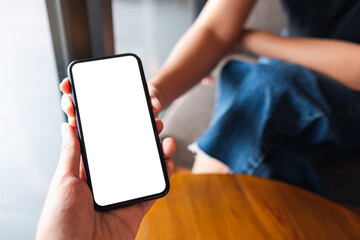 Mockup image of a woman holding and showing white mobile phone with blank black desktop screen to her friend