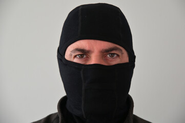 Portrait of a serious man wearing black face mask looking at camera