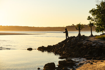 Silhouette of Man Standing on Rock Fishing at Sunset Time in Noosa, Queensland, Australia © nicolas