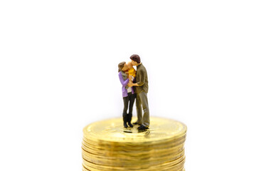 Money, Financial, Business, Cryptocurrency,  Security and Family concept. Parent and child miniature figures hug and kiss together standing on stack of gold Bitcoin coins isolated on white background.
