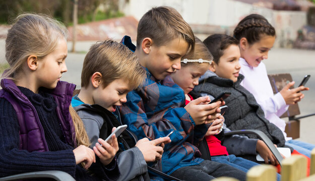 Outdoor portrait of spanish girls and boys playing with phones.
