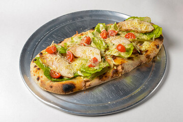 Pinza with chicken, cherry tomatoes, lettuce salad and Worcestershire sauce cooked in an oven with wood