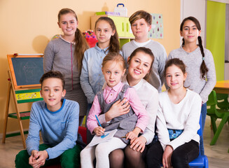 Portrait of elementary age kids with teacher sitting in classroom