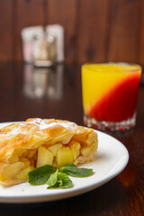 Slice of delicious fresh baked Rustic Apple Pie served on a white plate on wooden table background.