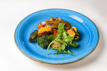 Delicious grilled vegetables served on a blue plate over white background. BBQ Grill concept.