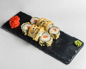 Japanese Sushi Roll - Warm Sushi Roll with Salmon and Cream Cheese served on a black board over white background.
