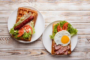 Waffle wholesome breakfast. Sour waffles with grilled sausages, fried eggs, delicious sauce and fresh vegetables.
