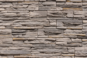 Fototapeta premium The wall is made of gray artificial stone. Multi-format decorative stone. Landscape design 