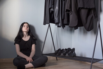 teen girl in black jeans and a t-shirt near  hanger with black clothes