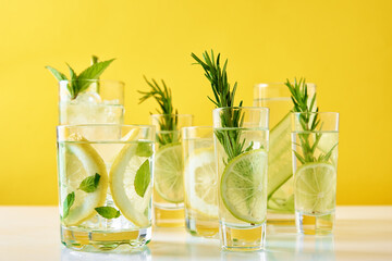 Summer alcoholic cocktail. Refreshment lemon soda drink. Gin and tonic with lime and rosemary on yellow background - obrazy, fototapety, plakaty