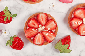 Single strawberry tartlet pastry topped with fruits and white chocolate sprinkles - obrazy, fototapety, plakaty