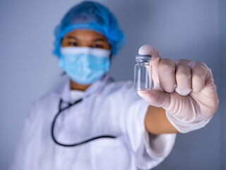 Studio portrait of a female doctor wearing a mask and wearing a hat. in the hand of the vaccine bottle and stretched out his arms in front standing on a white background. studio shot background.