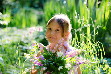 Portrait of a six year old girl with bouquet of flowers in the forest.