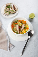 Mackerel fish soup with lime, chili and green pea on white table.