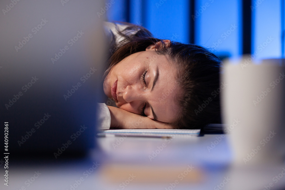 Poster entrepreneur working overtime on marketing project, falling asleep on desk while looking at financia