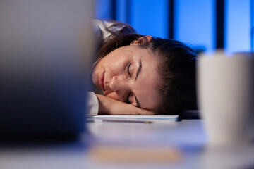 Entrepreneur working overtime on marketing project, falling asleep on desk while looking at financial documents trying to respect the deadline. Employee using modern technology network wireless