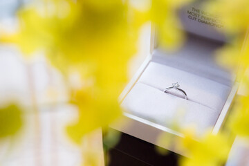 A proposal ring is placed in the white ring box with yellow petals in the foreground