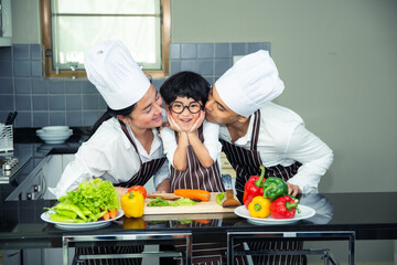 Asian woman young mother with son boy cooking salad food with vegetable holding tomatoes and carrots, bell peppers on plate for happy family cook food enjoyment lifestyle kitchen in home