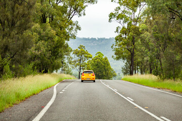 Yellow car with p plate driving down country road