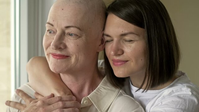 Young woman hugs her sick mom after chemotherapy. Love, care and support in the family of a cancer patient.