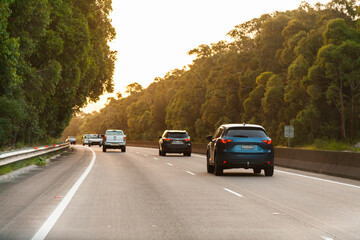 Cars driving down highway road overtaking one another at sunset