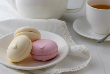 Sweet marshmallows with cup of tea on white wooden table. Closeup view.