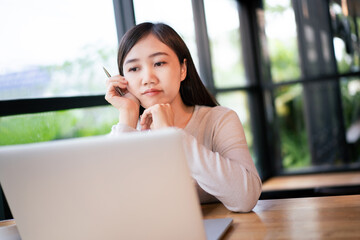 Fototapeta premium Happy young Asian woman using laptop computer for working at workspace in coffee shop.