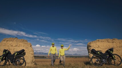 The man and woman travel on mixed terrain cycle bike touring with bikepacking. The two people...
