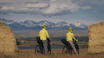 The man and woman travel on mixed terrain cycle bike touring with bikepacking. The two people...