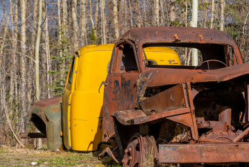 Rusty abandoned old trucks in vintage themed shot with boreal forest in background. Taken in Yukon, Canada. 