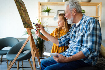 Happy smiling grandfather and grandchild painting together. Family, generation, happiness concept