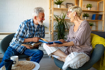 Mature couple relaxing at home and reading book together