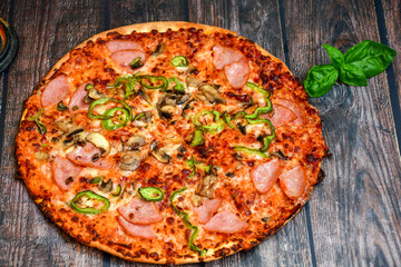  Close up of   classic  italian pizza   with ham. Fresh basil,tomato sauce ,mozzarella cheese , mushrooms and  green peppers