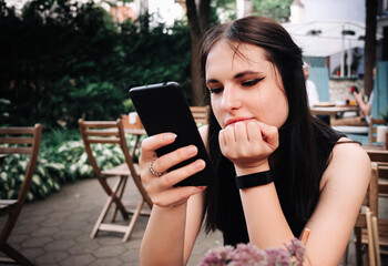 young woman or teenage girl using mobile phone in cafe outdoor