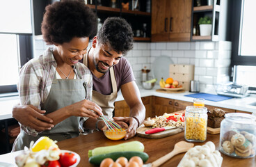 Beautiful young couple having fun and laughing while cooking in kitchen