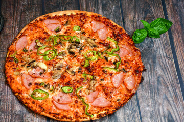  Close up of   classic  italian pizza   with ham. Fresh basil,tomato sauce ,mozzarella cheese , mushrooms and  green peppers