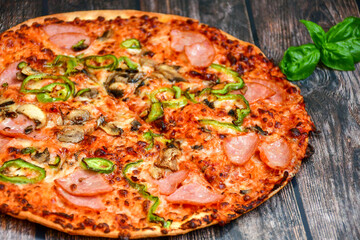  Close up of    hot italian pizza   classic ham. Fresh basil,tomato sauce ,mozzarella cheese , mushrooms and  minced meat .Concept poster for Restaurants or pizzerias. Top view