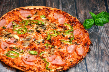  Close up of    hot italian pizza   classic ham. Fresh basil,tomato sauce ,mozzarella cheese , mushrooms and  minced meat .Concept poster for Restaurants or pizzerias. Top view