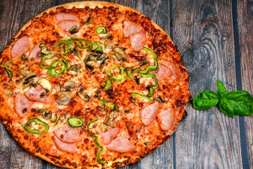  Close up of    hot italian pizza   classic ham. Fresh basil,tomato sauce ,mozzarella cheese , mushrooms and  minced meat .Concept poster for Restaurants or pizzerias. Top view