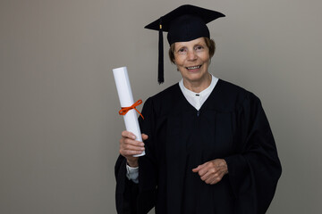 smiling older woman graduate in graduation gown holding diploma