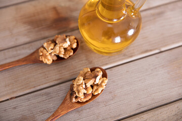 Walnut kernels in a wooden spoon and a bottle of walnut oil