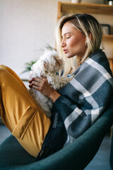 Portrait of beautiful young woman with dog playing at home.